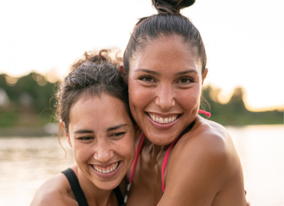 Two sisters hugging at the beach after a swim
