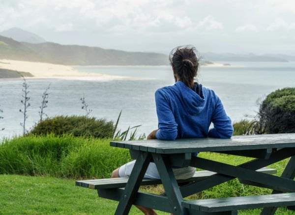 Young man at NZ beach looking out to sea