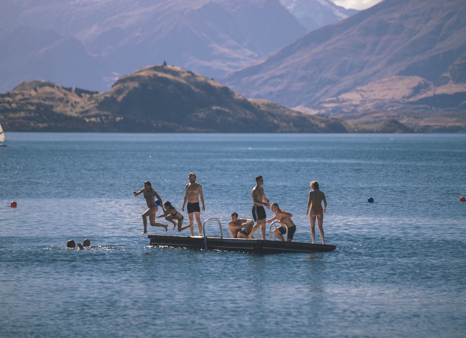Swimmers jumping off a pontoon into Lake Wanaka New Zealand
