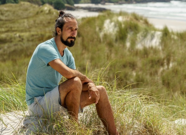 Man sitting in the sand dunes looking thoughtful