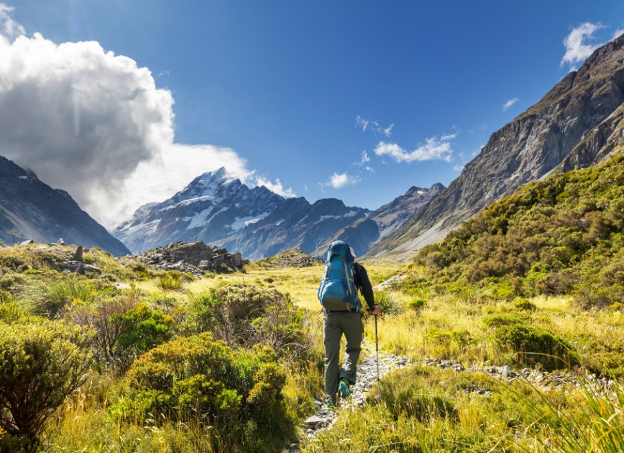 Hiker with pack on path towards New Zealand mountains