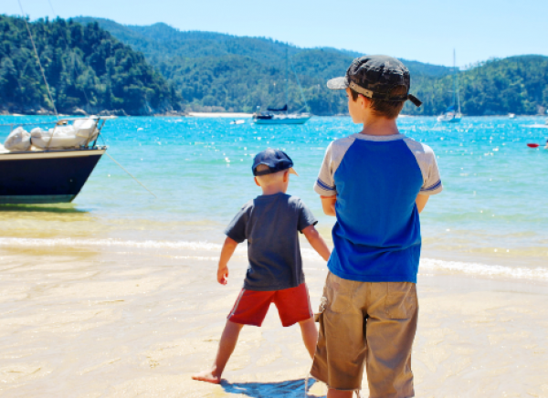 Two boys at sunny beach in Abel Tasman, New Zealand