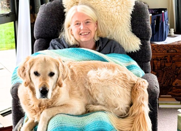 Woman sitting in lazy boy chair with rug and large dog on her knee